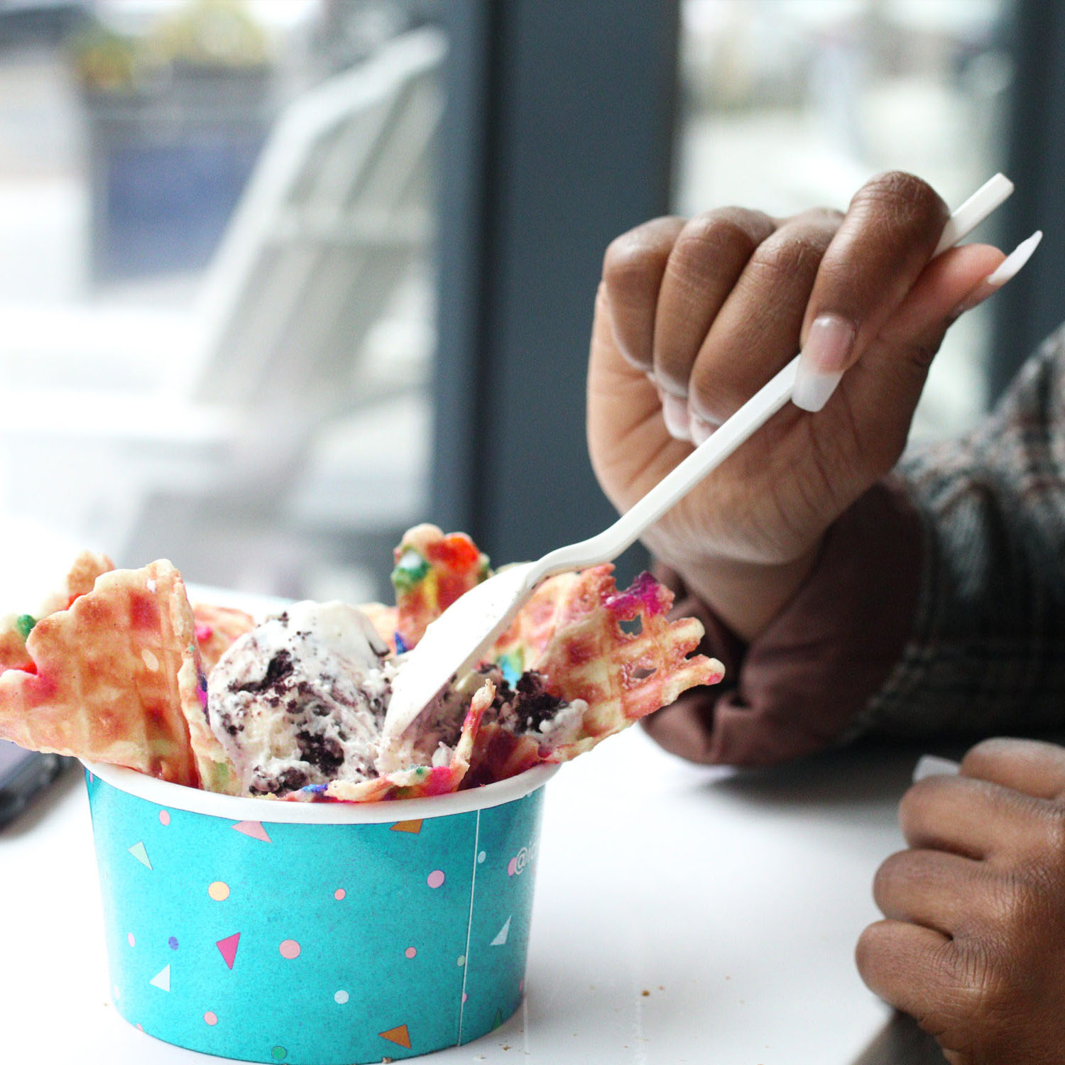 person scooping ice cream from a bowl with a plastic spoon